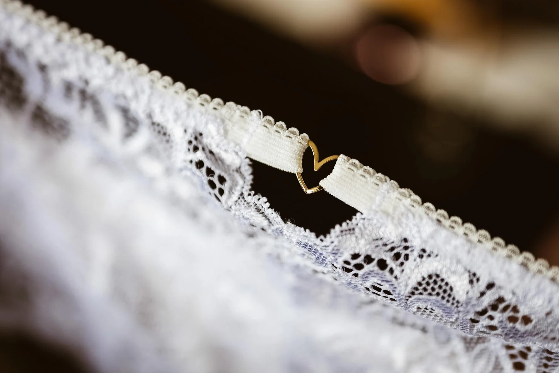 Feine weiße Spitze mit einem kleinen goldenen Herz