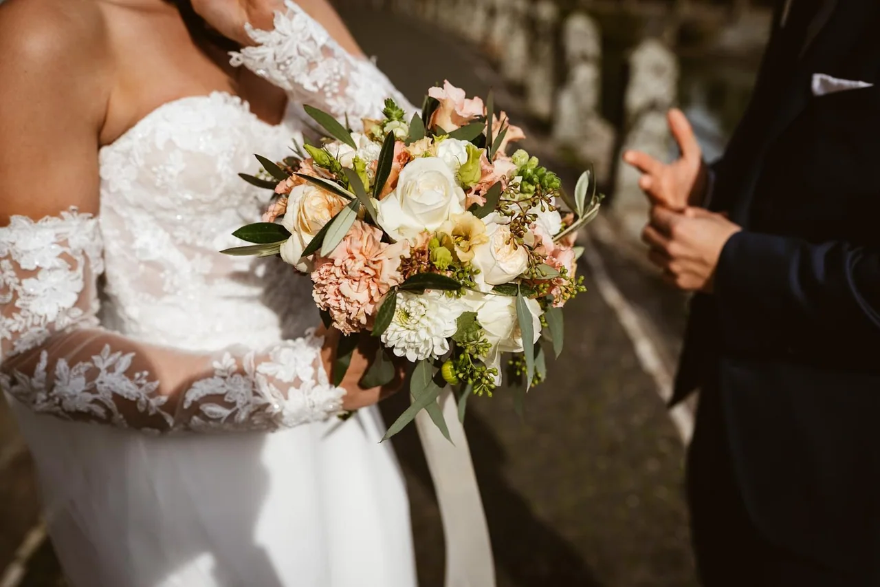 Hände richten das Brautkleid und den Strauß