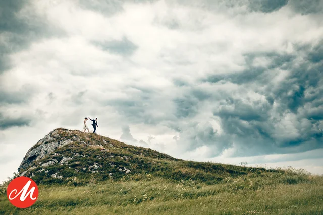 Ein Paar auf einem Hügel unter dramatischen Wolken; Masters-Auszeichnung mit rotem M