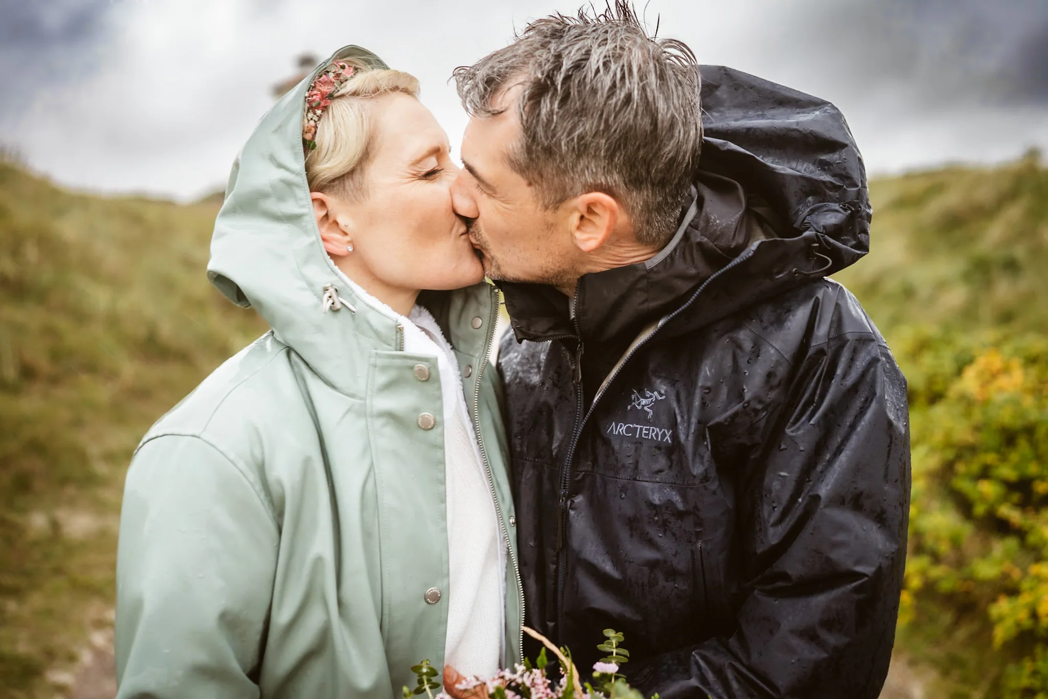 Mella und Christoph küssen sich in Regenjacken