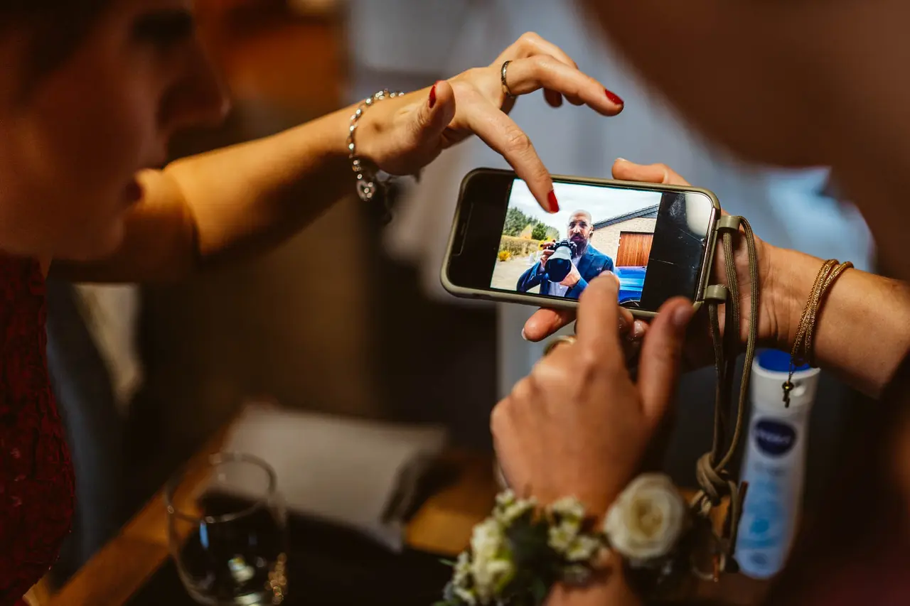 Hochzeitsgäste betrachten auf einem Handy ein Foto von Marc bei der Arbeit