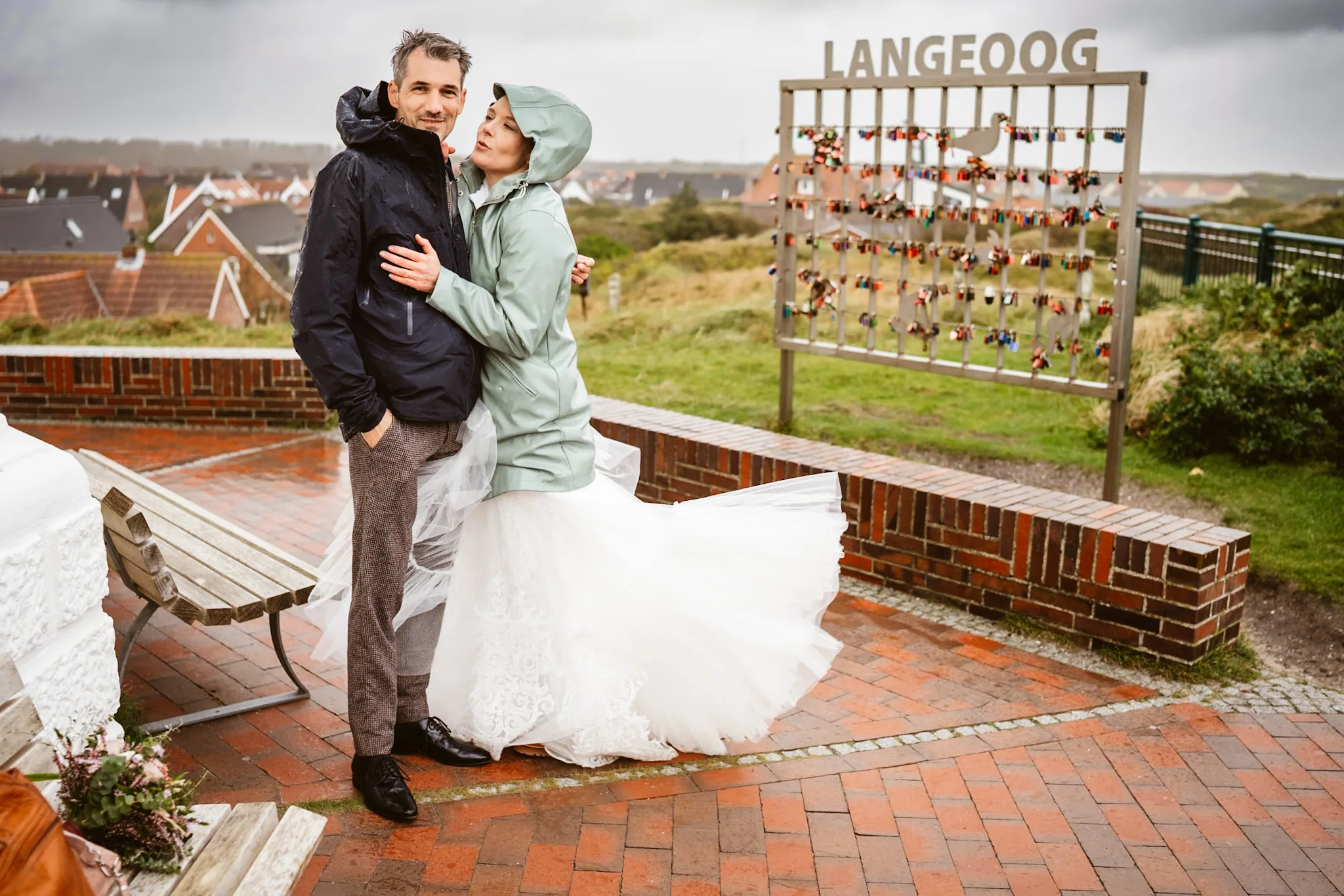 Mella und Christoph in Regenjacken vor dem Langeoog-Schild
