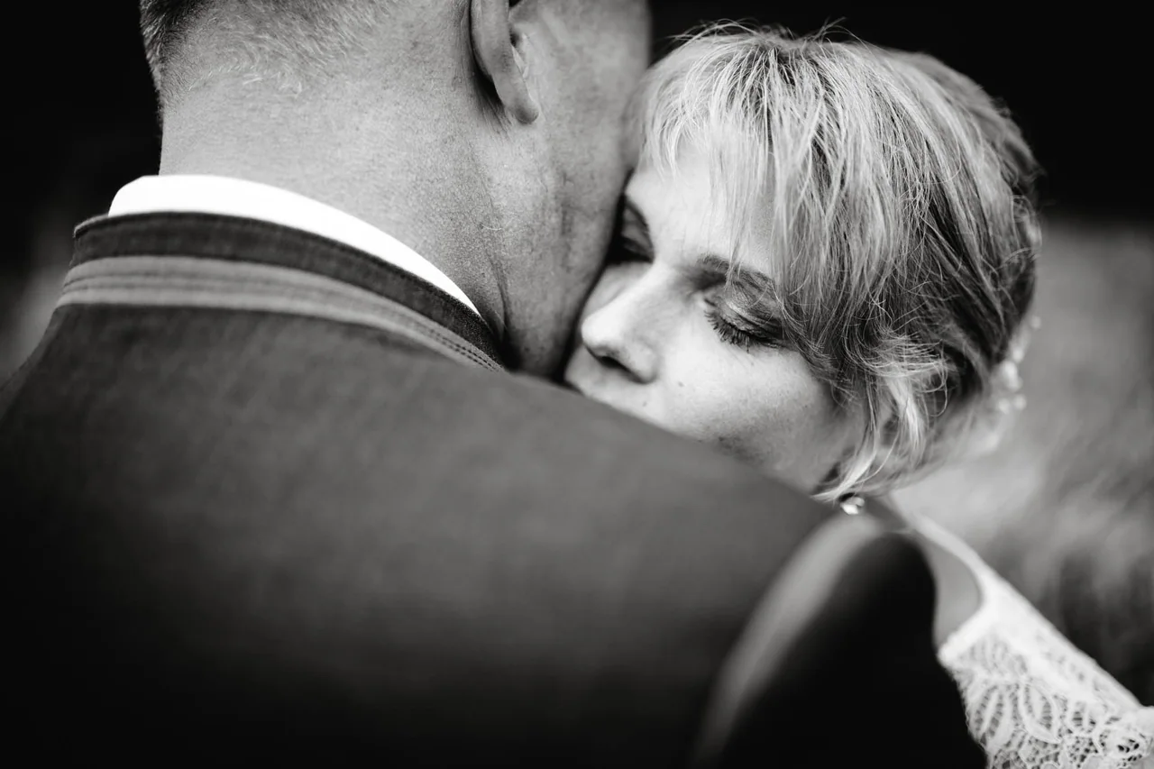 Frau umarmt einen Mann bei der Hochzeit