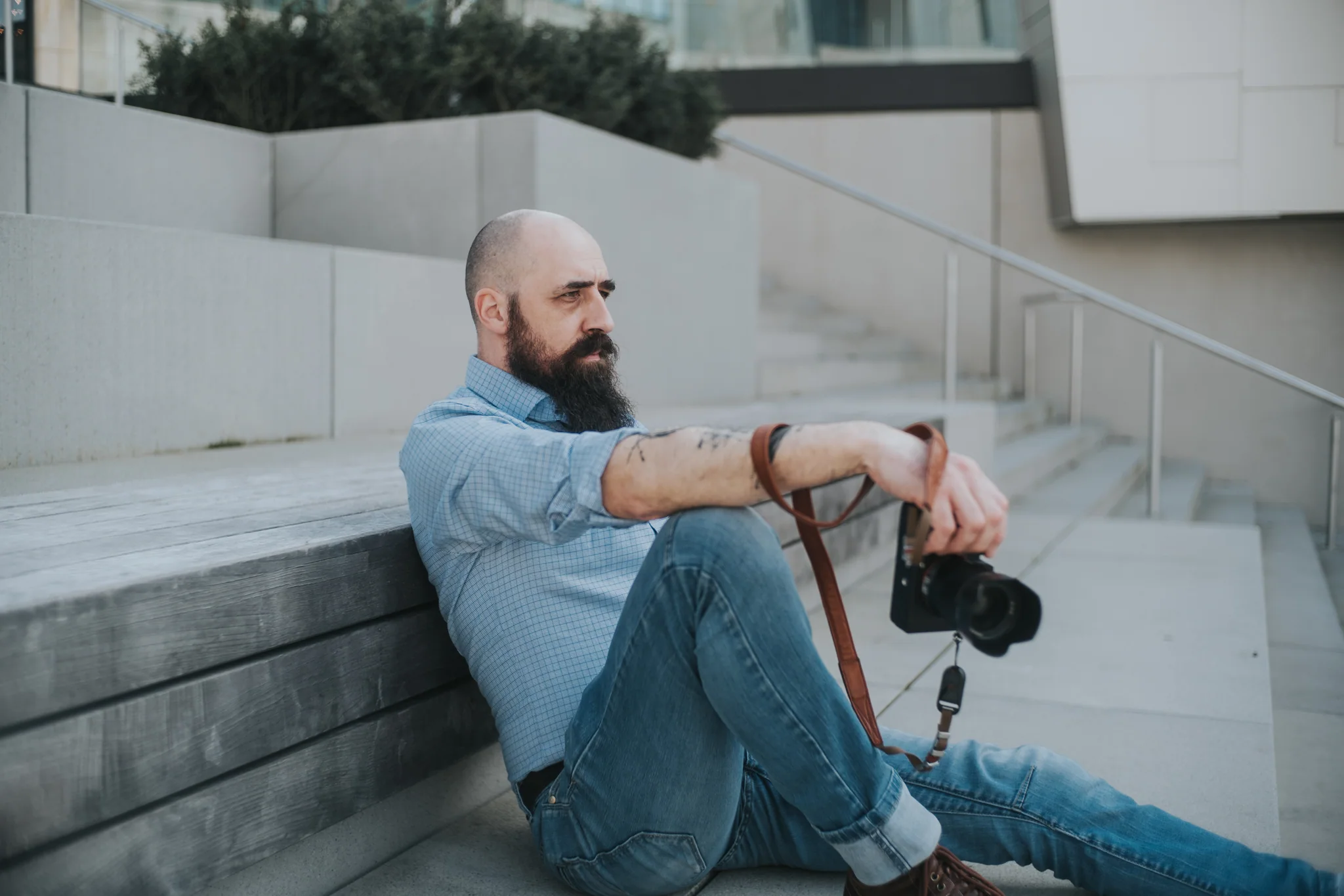 Marc sitzt draußen auf einer Treppe und hält seine Kamera
