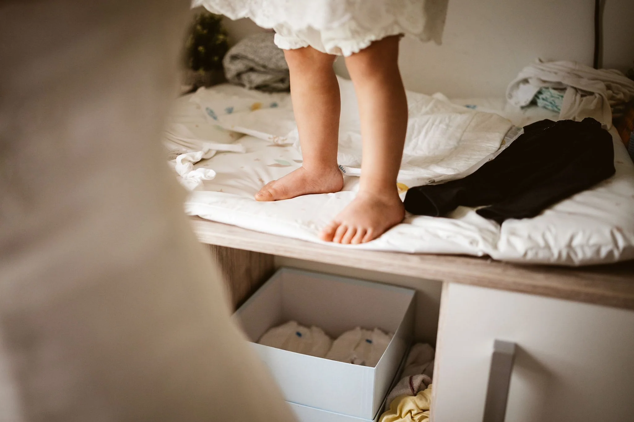 Kind steht beim Getting Ready barfuß auf einem Bett
