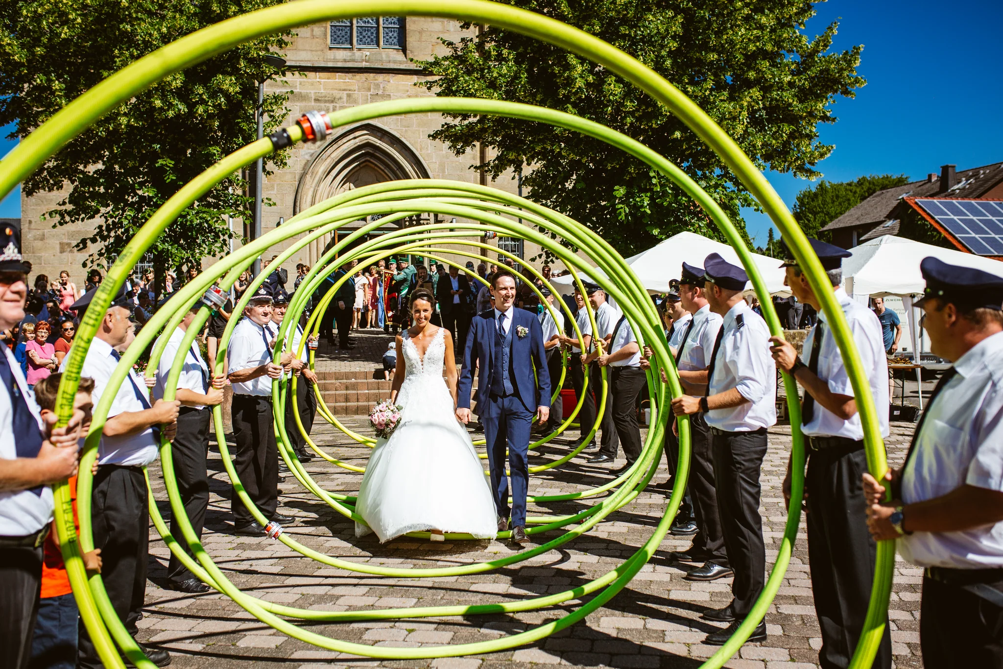 Hochzeitspaar läuft durch einen farbenfrohen Spalier der Gäste
