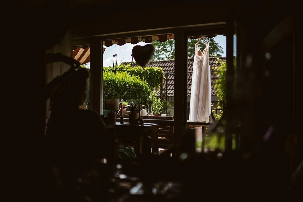 Blick aus dem noch dunklen Zimmer zum Brautkleid