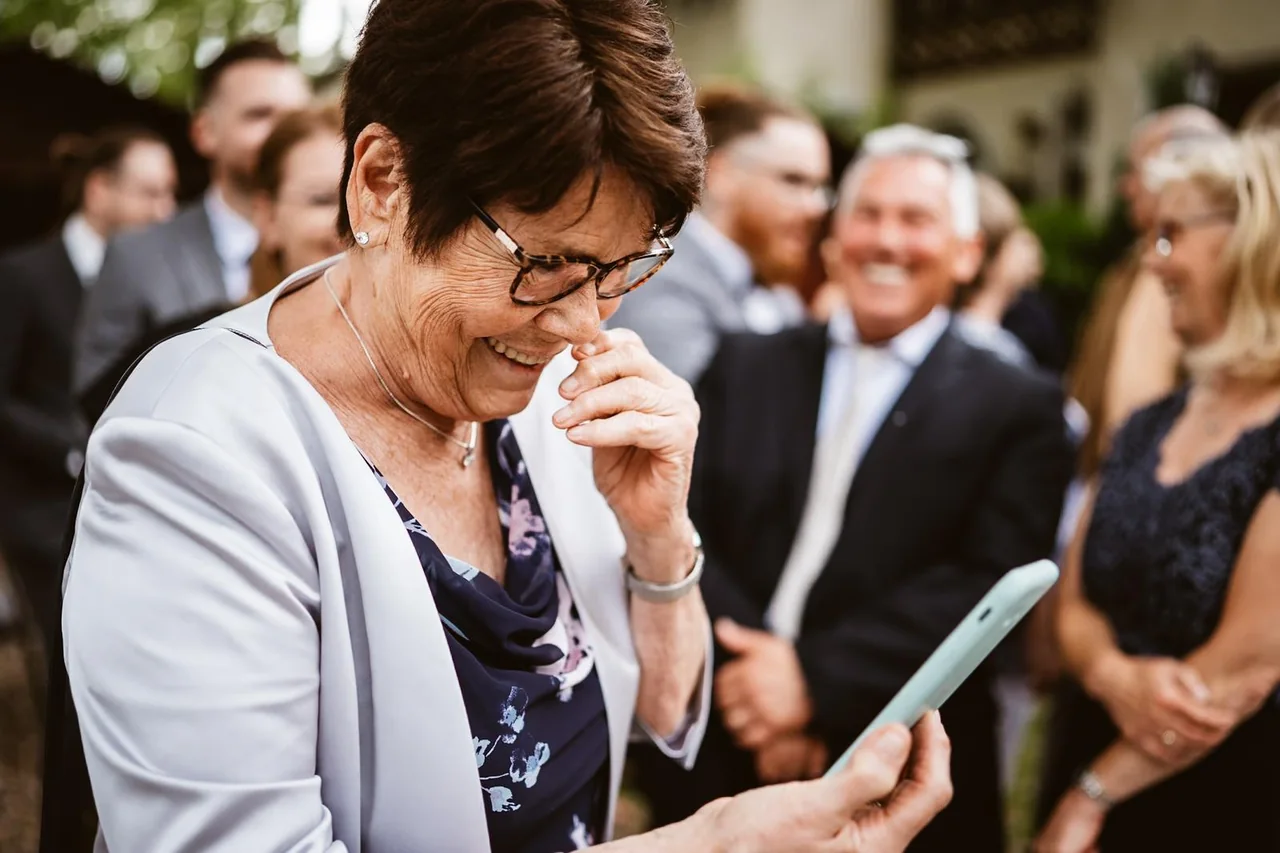 Die Oma schaut gerührt auf ihr Handyfoto