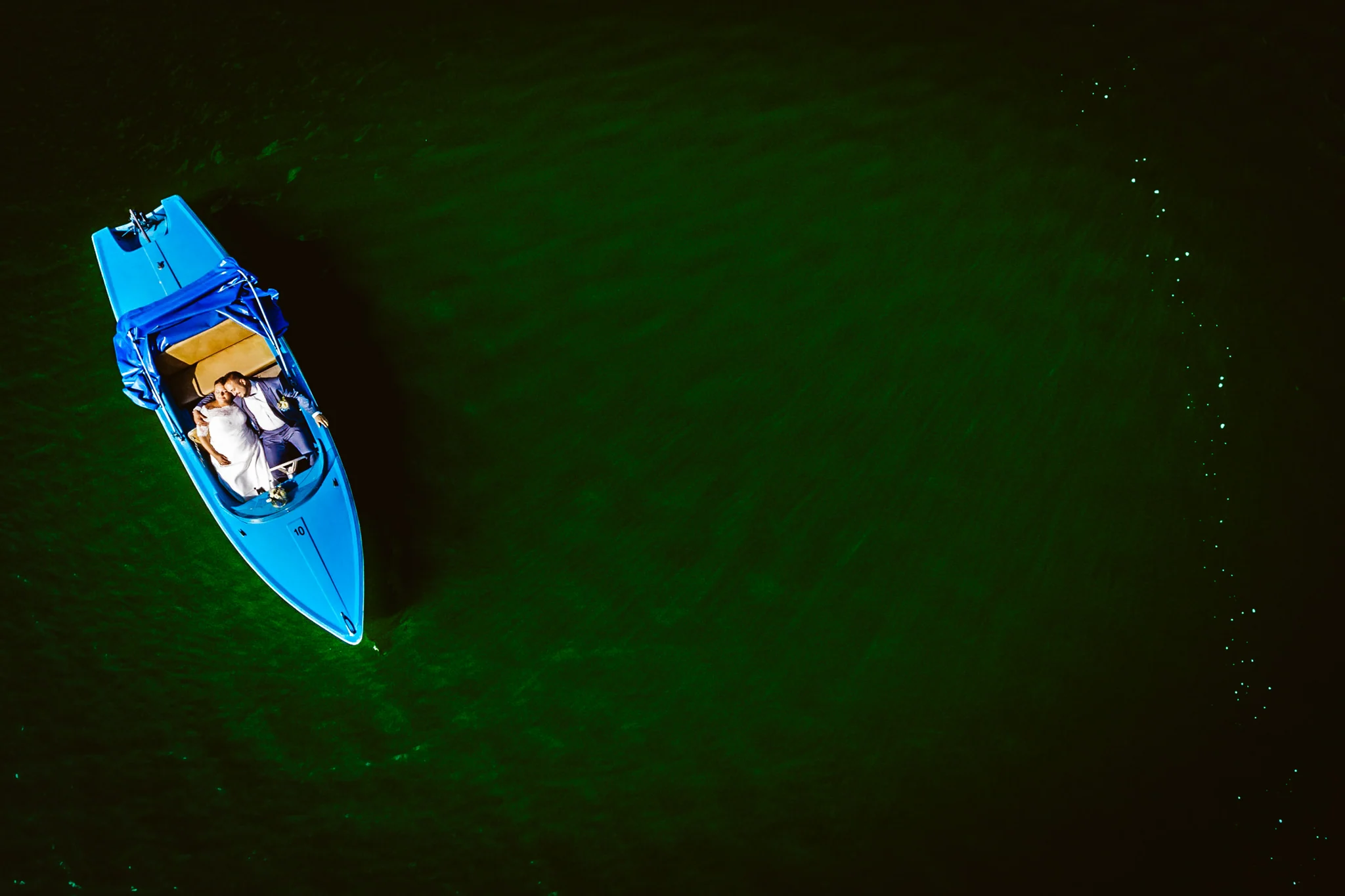 Blaues Boot auf dunklem Wasser von oben