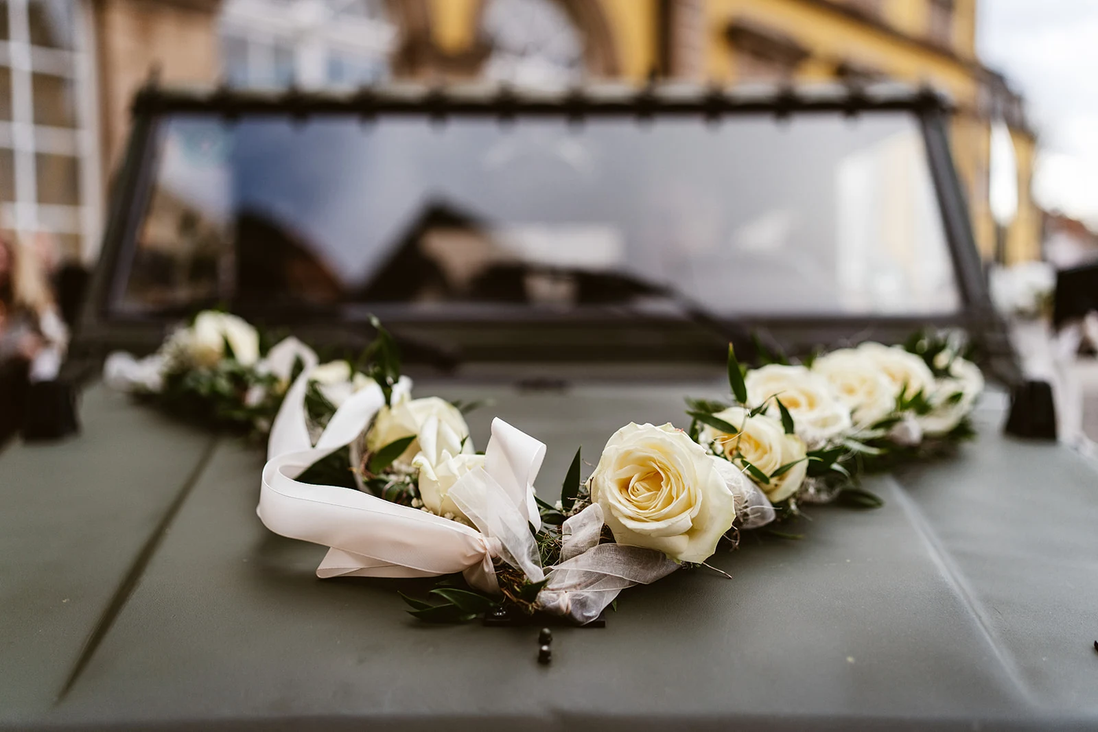 Weiße Rosen schmücken die Motorhaube des Hochzeitsautos