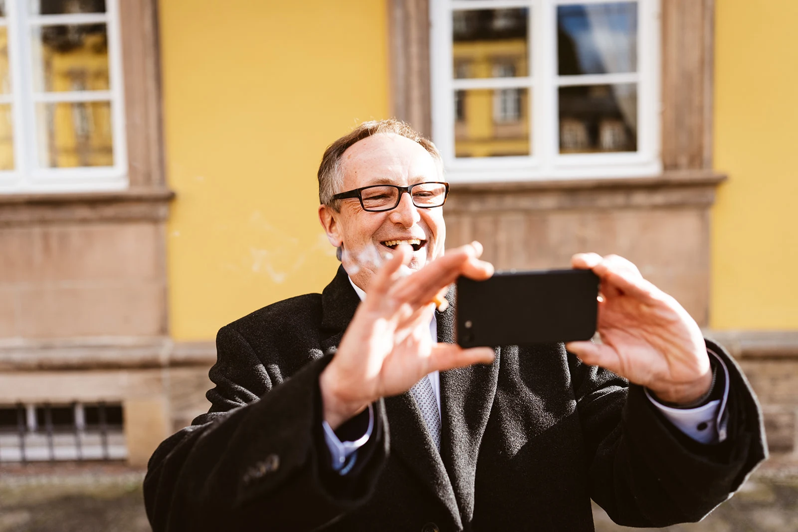 Ein Gast hält lachend sein Handy zum Fotografieren hoch