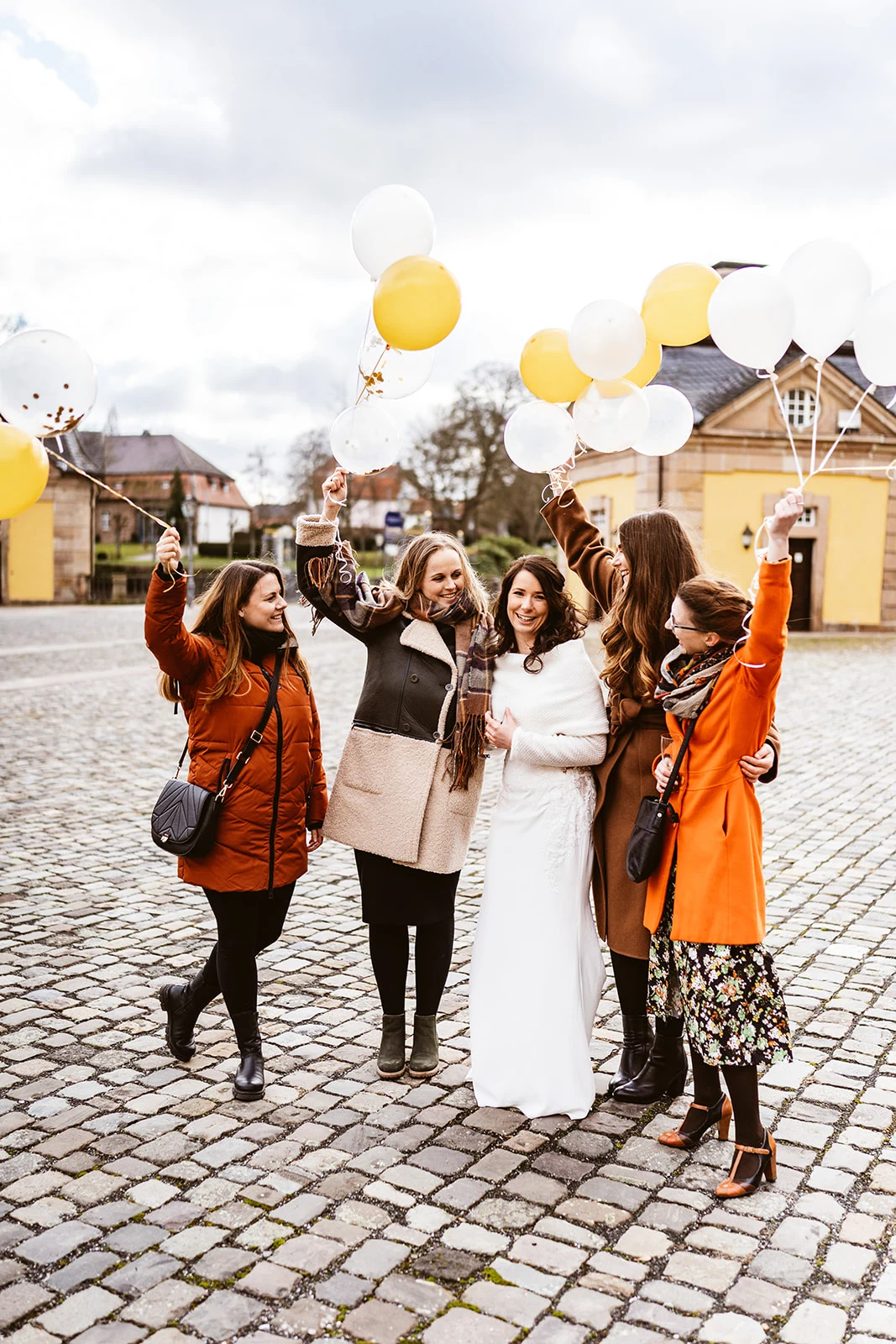 Gäste mit gelben und weißen Luftballons vor dem Schloss